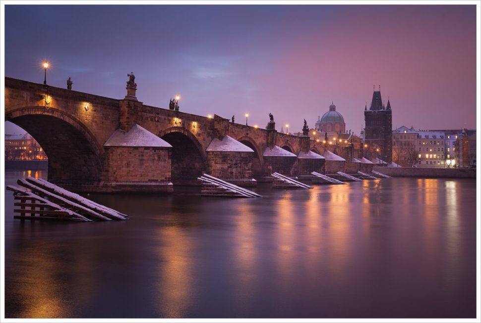 Pohled na mlhavý a světly nasvícený Karlův most v historické části Prahy