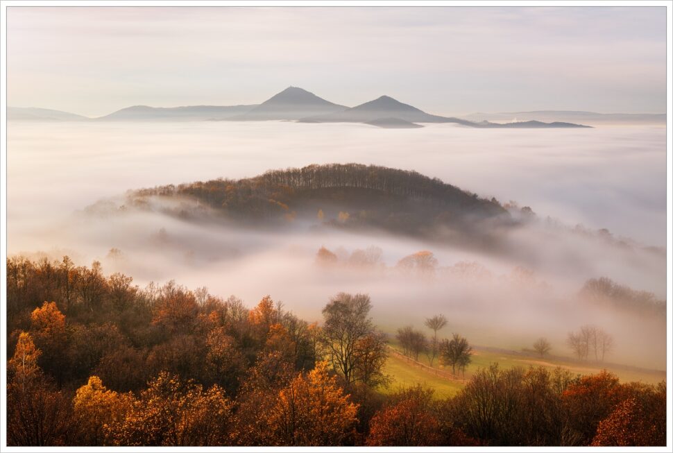 Podvečerní výhled z Holého vrchu. Z podzimní inverze vystupují dominanty milešovského středohoří - Milešovka a Kletečná. Fotografický workshop podzimní České středohoří.